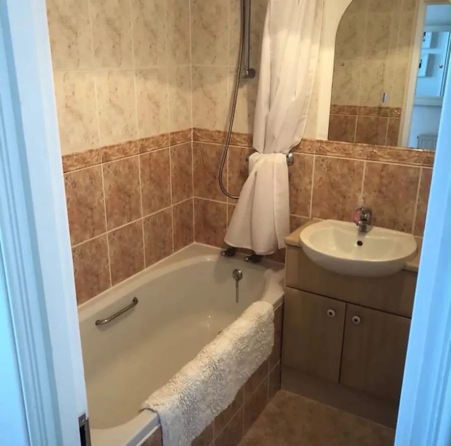 Original bathroom with brown tiles, bath and vanity